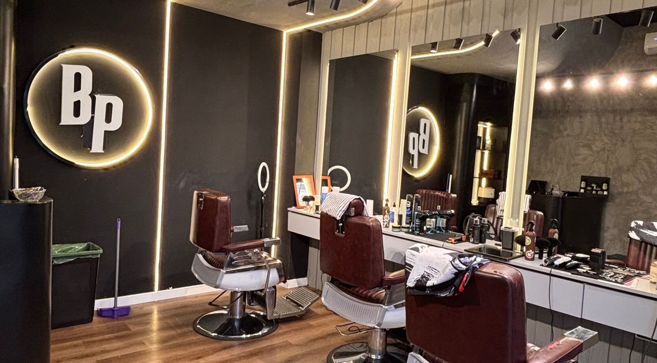 Interior moderno de Barberia en Córdoba, Córdoba, AR con sillas de barbero y espejo iluminado.