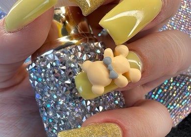 Uñas amarillas con diseño de osito en Garras Creative Nails by Pily García, Madras, Oregon, US.