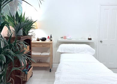 Tranquil massage room at Gem Massage Therapy, Enfield, England, GB with lush plants and a cozy treatment bed.