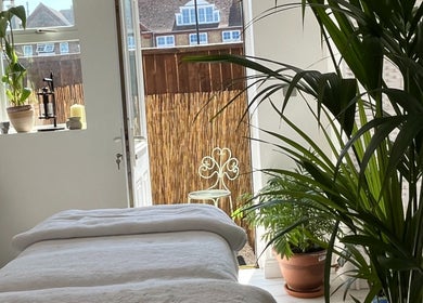 Relaxing massage room at Gem Massage Therapy, Enfield, England, GB with cozy bed and lush plants.