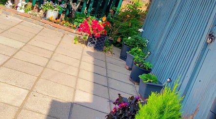 Charming patio garden outside Royal Beauty, Uxbridge, England, GB, with colorful flowers and lush greenery.