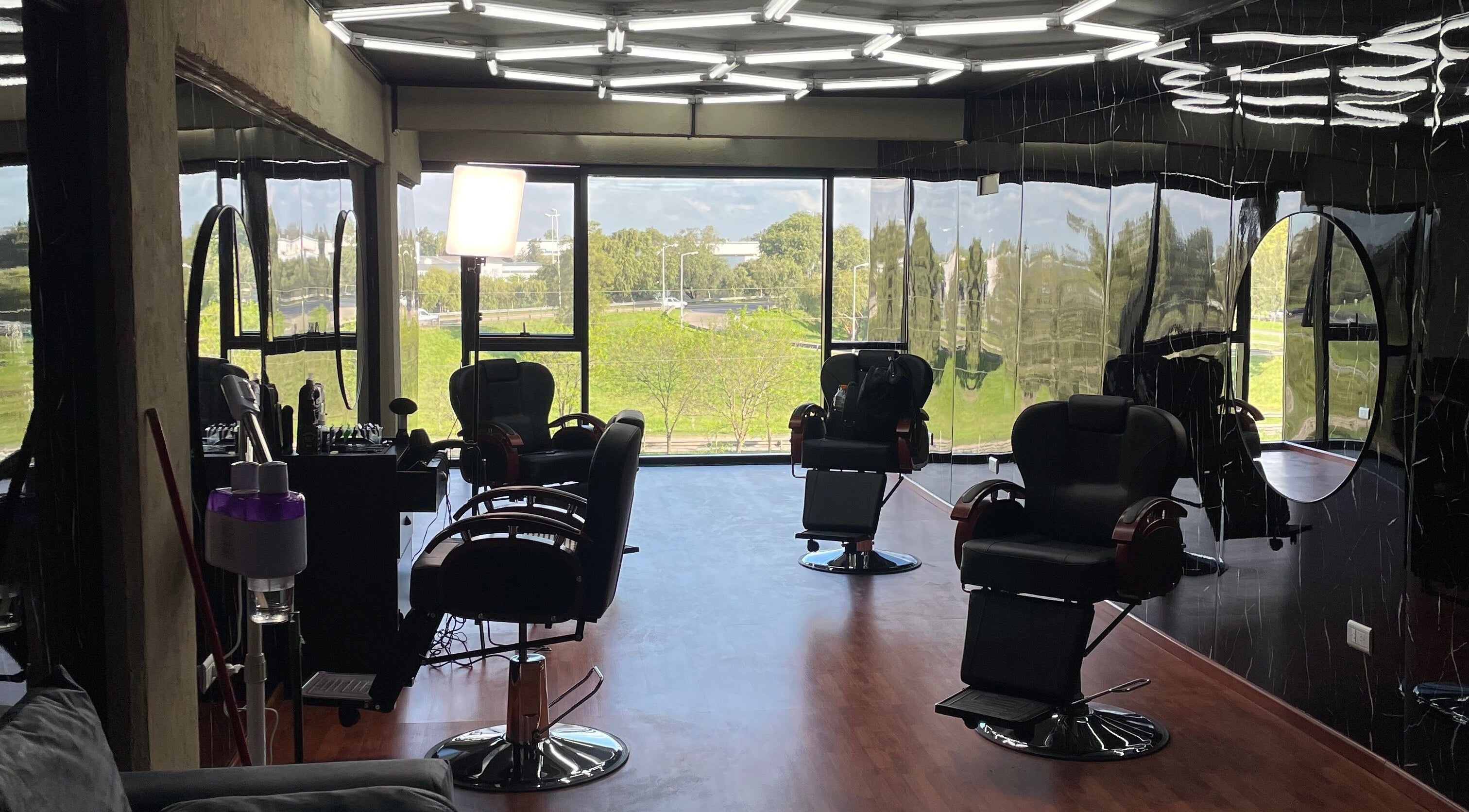 Interior moderno de Barbería Time Out en General Rodríguez, Buenos Aires con sillas elegantes y gran ventanal.