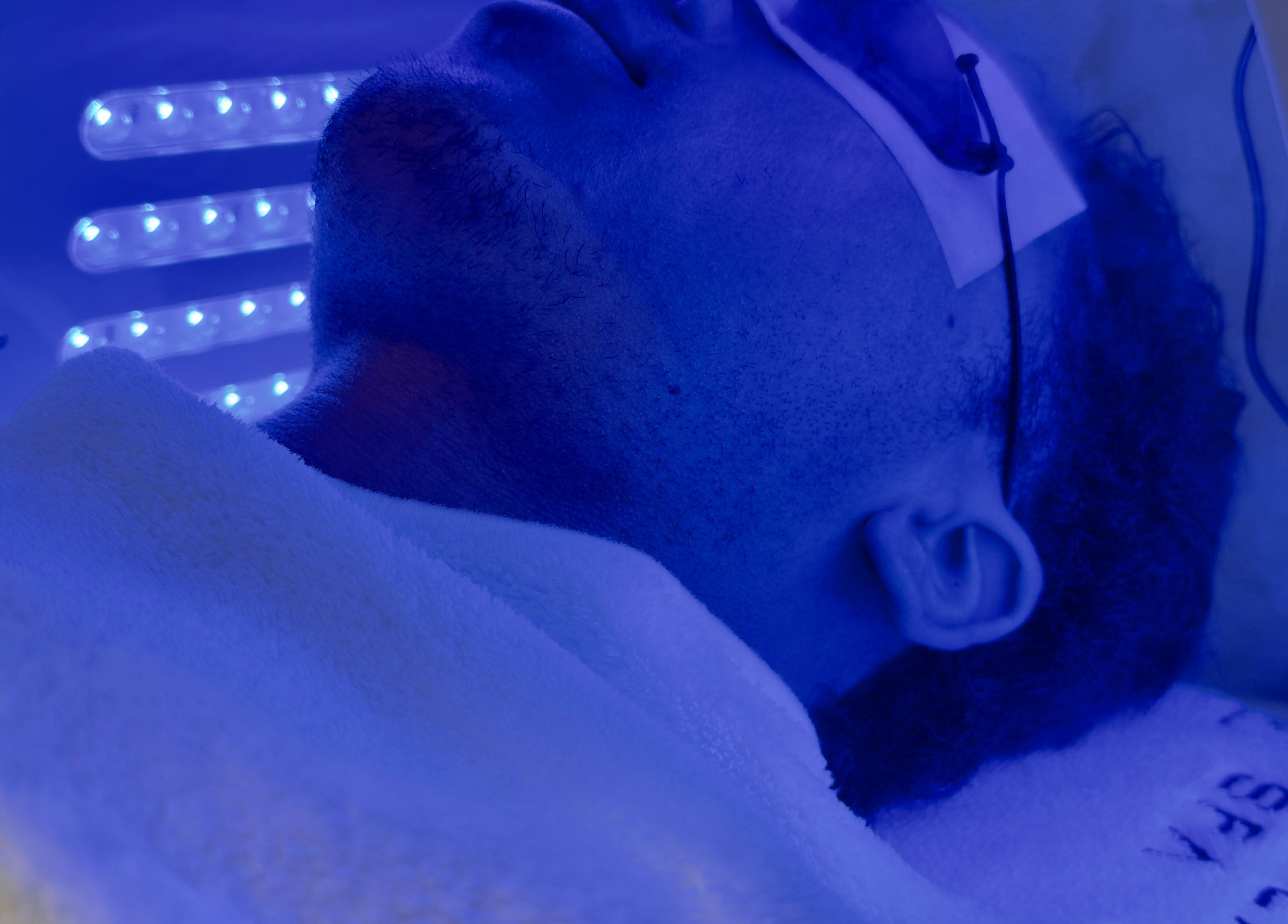 Man experiencing LED therapy at Solace Spa, Miami, Florida, US, under a soothing blue light.