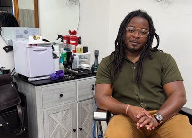 Chilly.Da.Barber at FAMA Cuts in Los Angeles, California, US, seated in a modern barbershop setup.