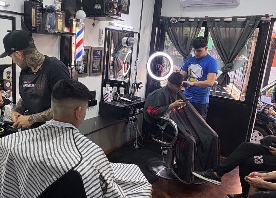 Interior de Salto Barbería en Villa Lugano, Ciudad Autónoma De Buenos Aires, con clientes recibiendo cortes.