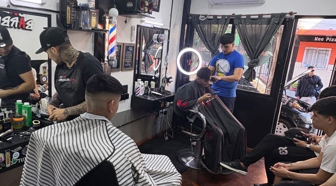 Interior de Salto Barbería en Villa Lugano, Ciudad Autónoma De Buenos Aires, con clientes recibiendo cortes.