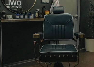 Stylish barber chair at OWL Barbershop, Rīga, LV, showcasing a modern, inviting grooming atmosphere.