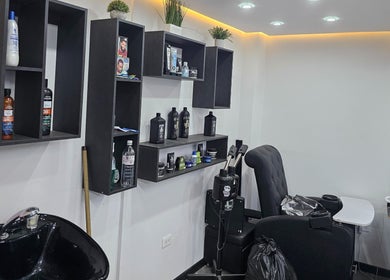 Interior moderno de Lest Barber Club, Tuluá, Valle Del Cauca, CO, con silla de barbería y estantería elegante.