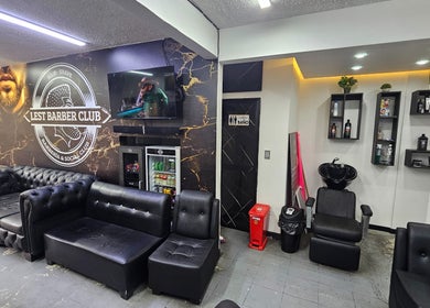 Interior moderno y elegante de Lest Barber Club en Tuluá, Valle Del Cauca, CO con sofás negros y decoración estilizada.
