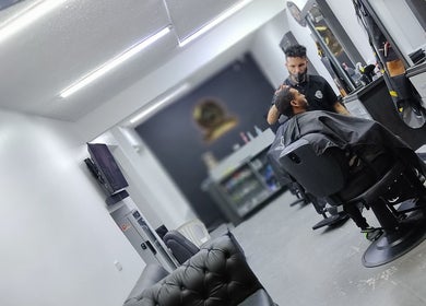 Interior moderno de Lest Barber Club en Tuluá, Valle Del Cauca, CO, con un barbero atendiendo a un cliente.