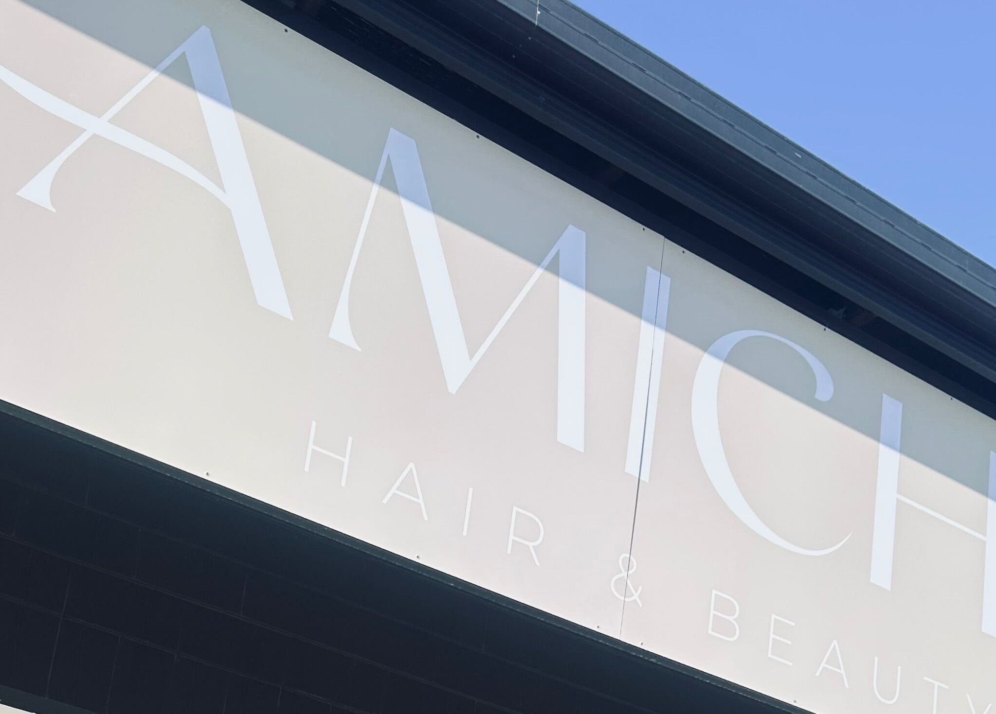 Elegant sign of Amiche Hair and Beauty located in Yamanto, Queensland, AU under a clear blue sky.