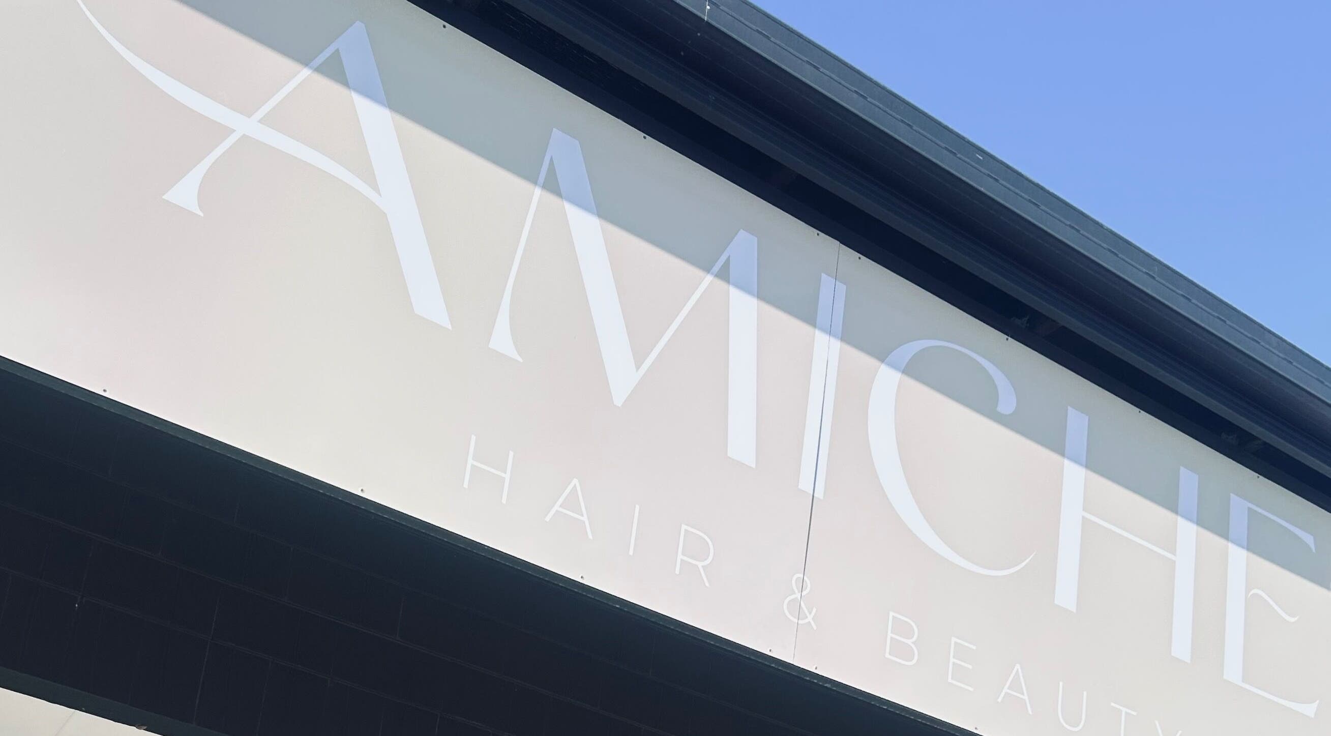 Elegant sign of Amiche Hair and Beauty located in Yamanto, Queensland, AU under a clear blue sky.
