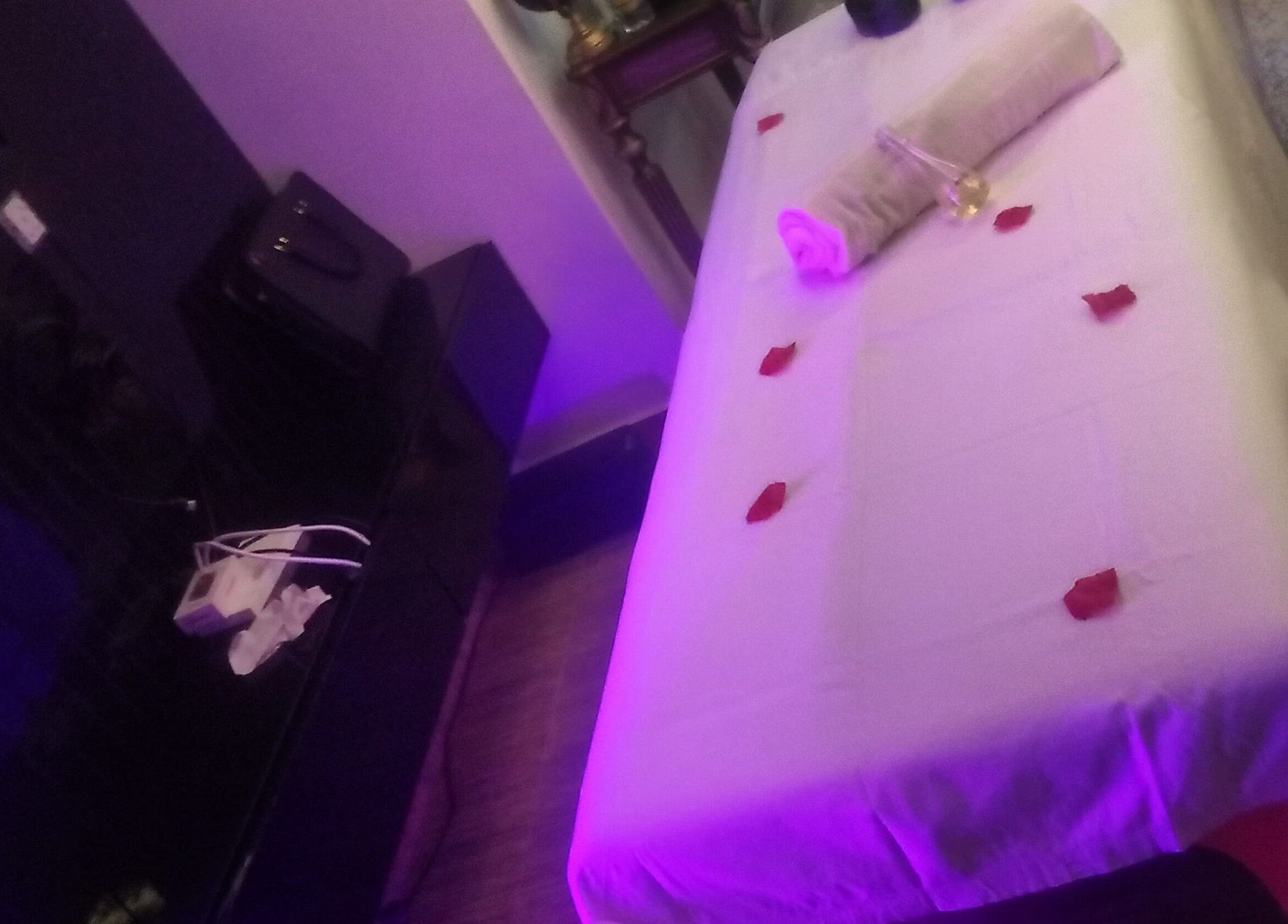 Tranquil massage table setup at Damme's Wellness in Lagos, Lagos, NG, adorned with rose petals and soft lighting.