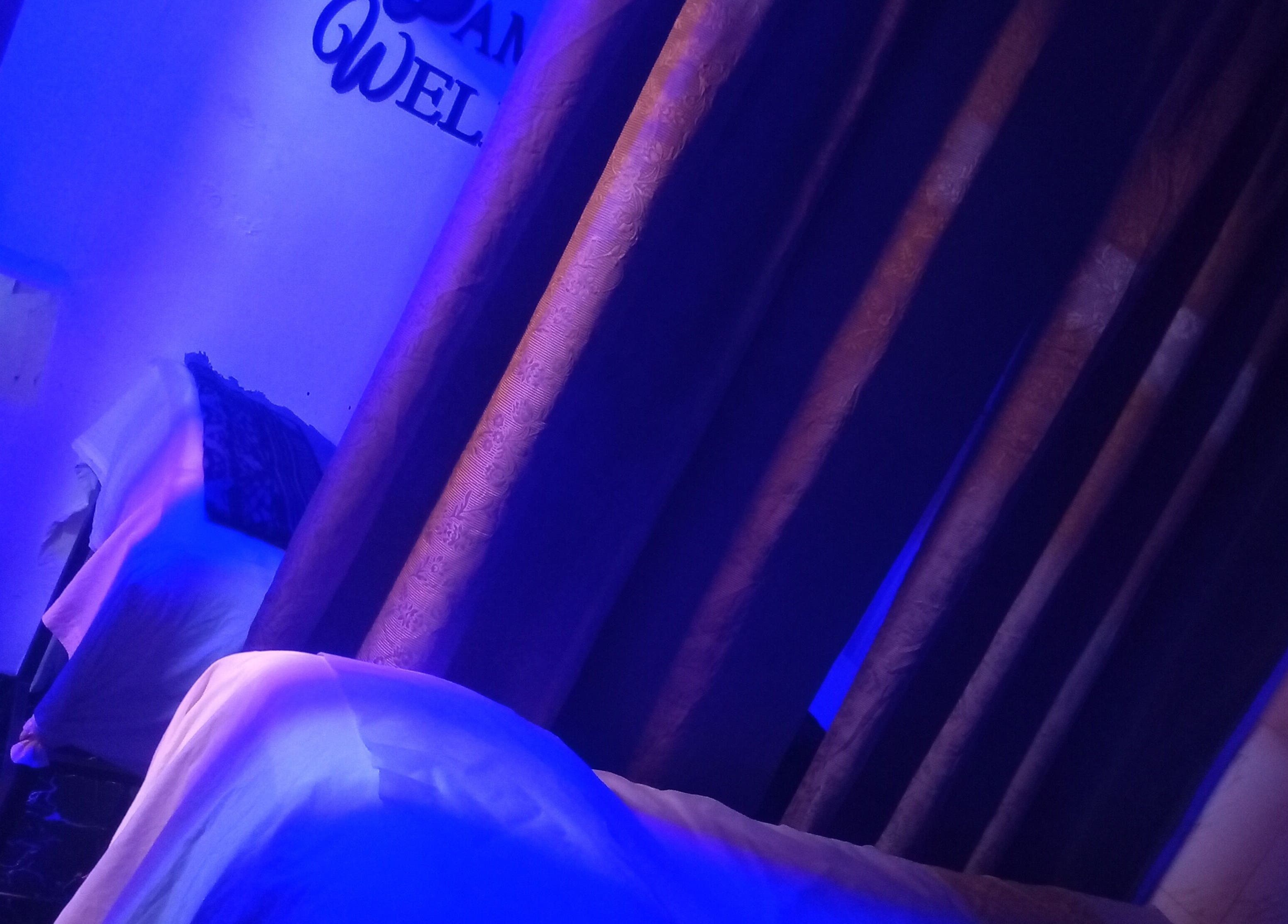 Peaceful treatment room at Damme's Wellness, Lagos, Lagos, NG with ambient blue lighting and cozy setting.