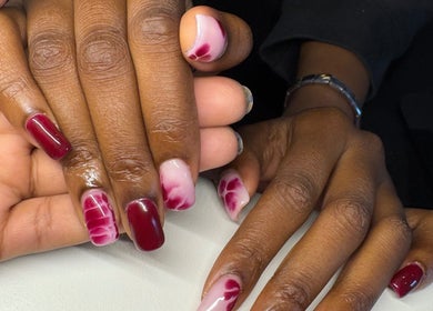 Elegant nail art at Nailed By Amii, Leeds, England, showcasing floral designs with red and pink hues.