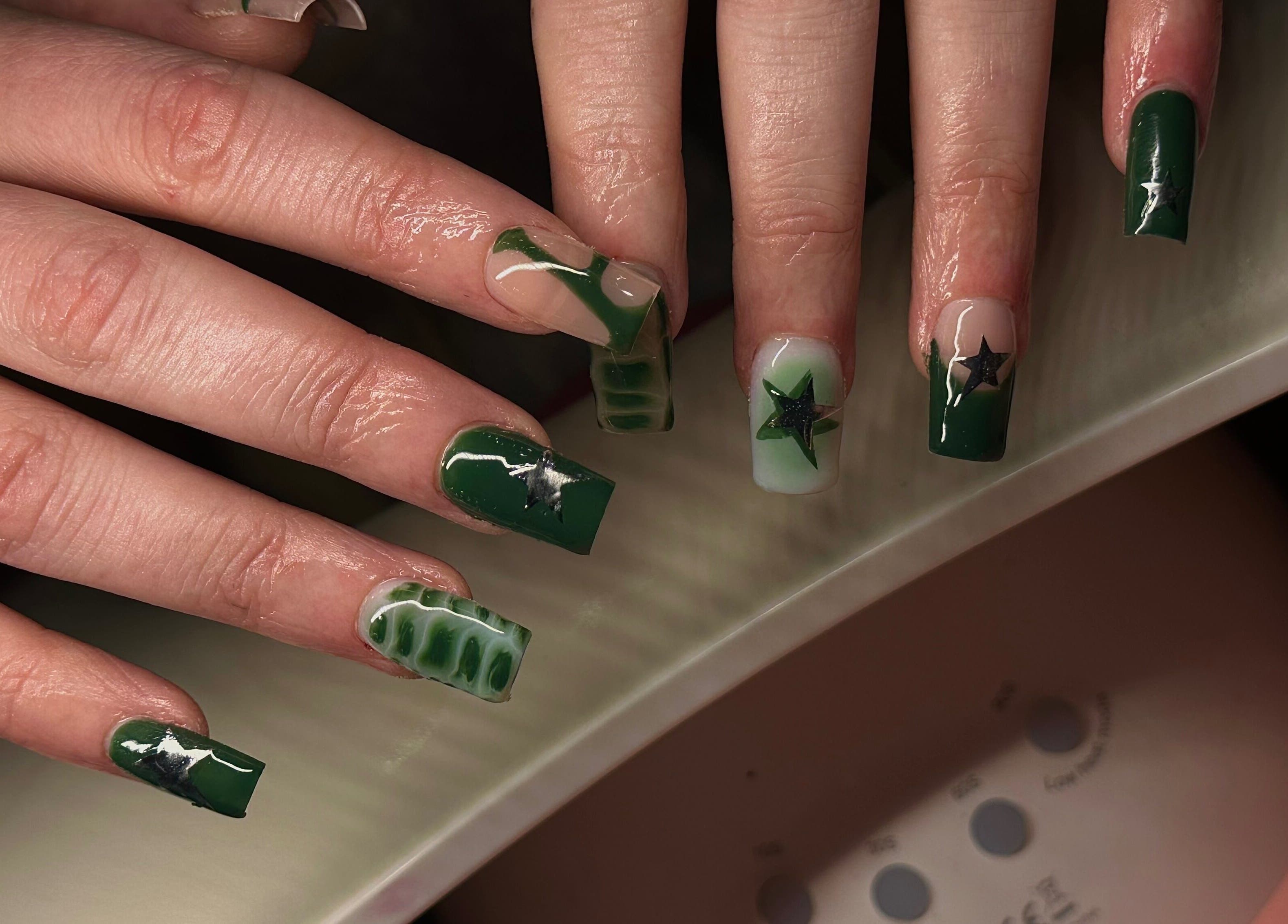Green nails with star designs at Nailed By Amii, Leeds, England, GB. Elegant and creative nail artistry.