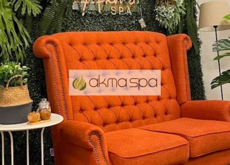 Elegant orange sofa at Akma Spa Melawati in Kuala Lumpur, lush plants enhance serene ambiance, inviting relaxation.