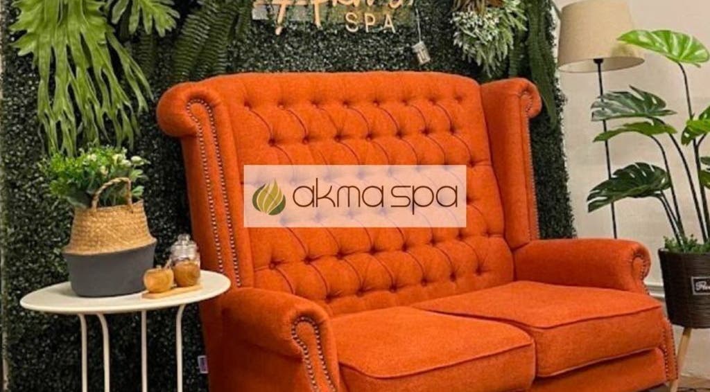 Elegant orange sofa at Akma Spa Melawati in Kuala Lumpur, lush plants enhance serene ambiance, inviting relaxation.