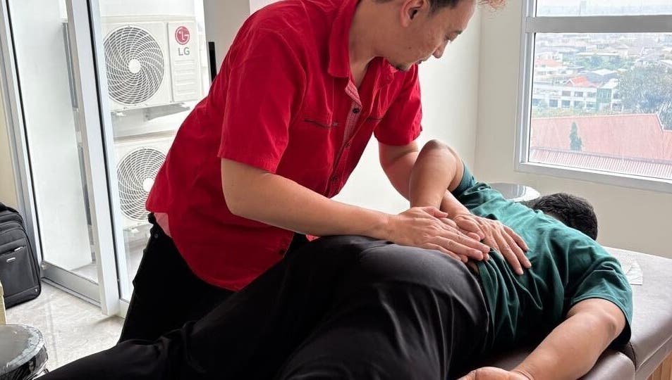 Terapis di PH Remedial Massage - Surabaya, Jawa Timur, memberikan perawatan pijat profesional di meja pijat.