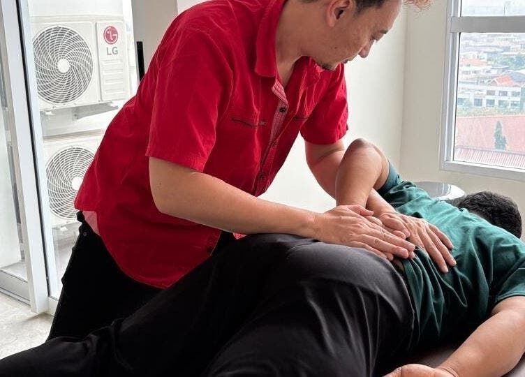 Terapis di PH Remedial Massage - Surabaya, Jawa Timur, memberikan perawatan pijat profesional di meja pijat.