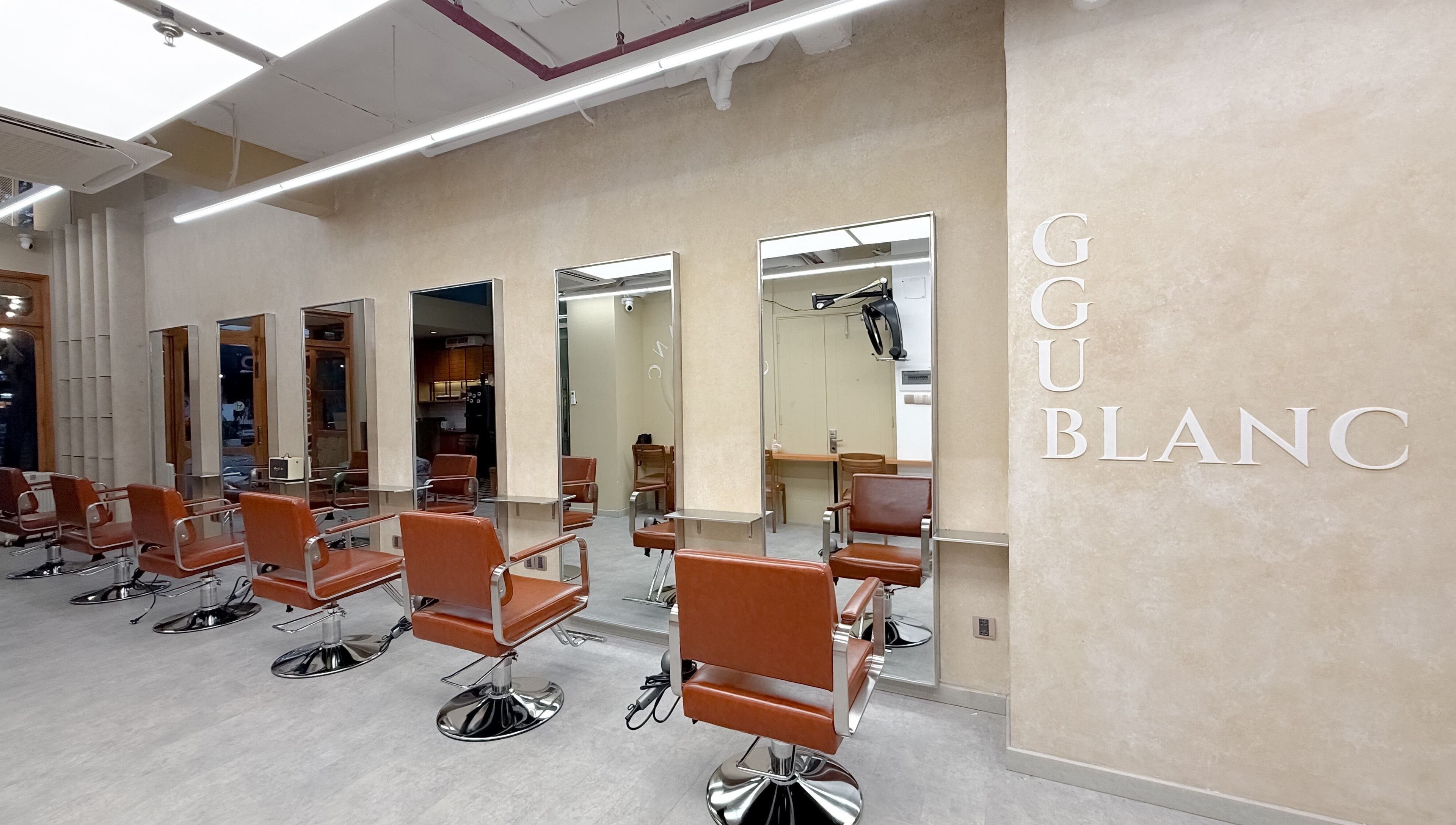 Nội thất hiện đại tại Ggublanc Hair, Hồ Chí Minh, VN với ghế da nâu và gương lớn.