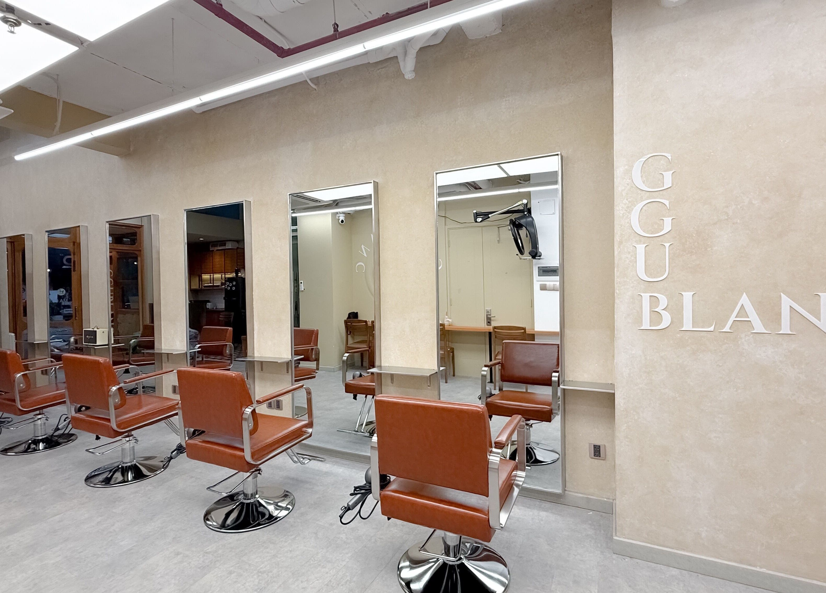 Nội thất hiện đại tại Ggublanc Hair, Hồ Chí Minh, VN với ghế da nâu và gương lớn.
