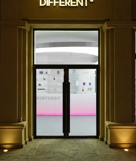 Front view of DIFFERENT Clinic's elegant entrance in Abu Dhabi, Abu Dhabi, AE with modern lighting and glass doors.