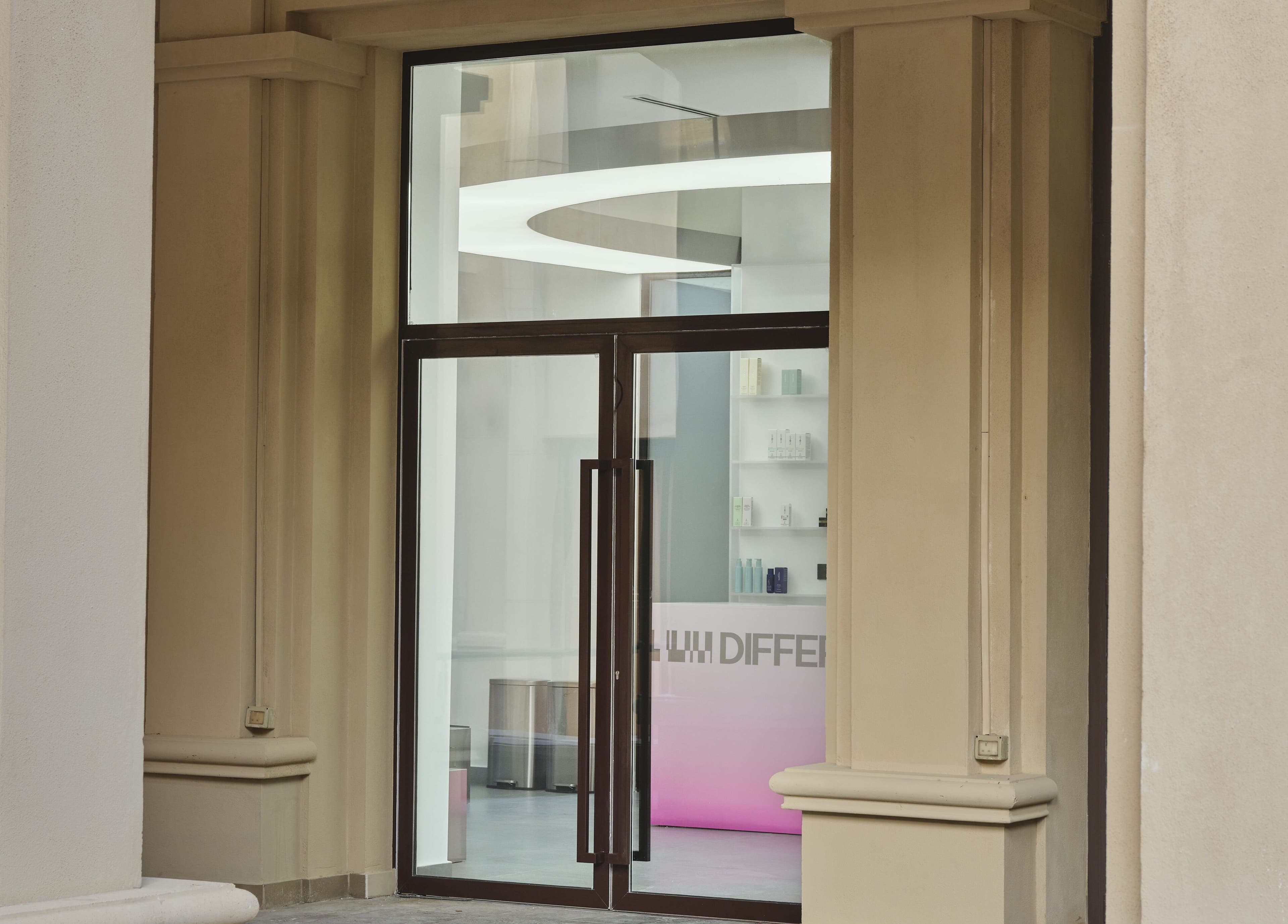 Entrance of DIFFERENT Clinic, a beauty and wellness venue in Abu Dhabi, Abu Dhabi, AE with a sleek glass door.