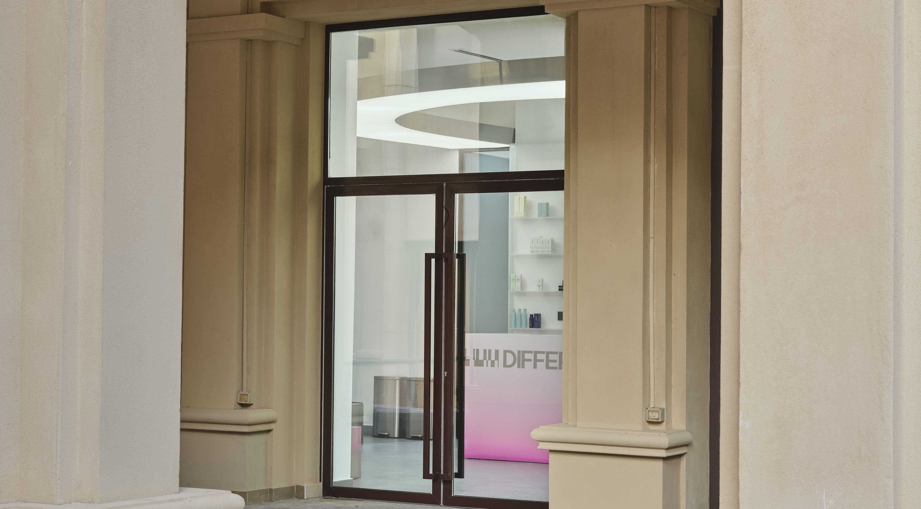 Entrance of DIFFERENT Clinic, a beauty and wellness venue in Abu Dhabi, Abu Dhabi, AE with a sleek glass door.