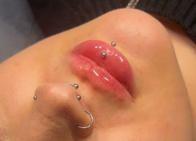 Close-up of lip piercings at Aesthetics By Kiki, Leeds, England, GB showcasing glossy lip treatment.