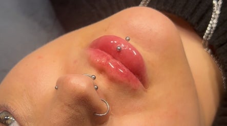 Close-up of lip piercings at Aesthetics By Kiki, Leeds, England, GB showcasing glossy lip treatment.