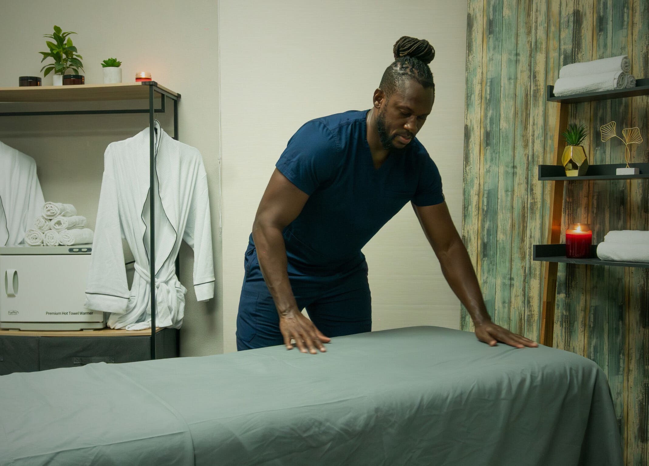 Therapist at Absolute Fitness Active Therapy Lounge in Bridgetown, Saint Michael, BB setting up a relaxing massage room.