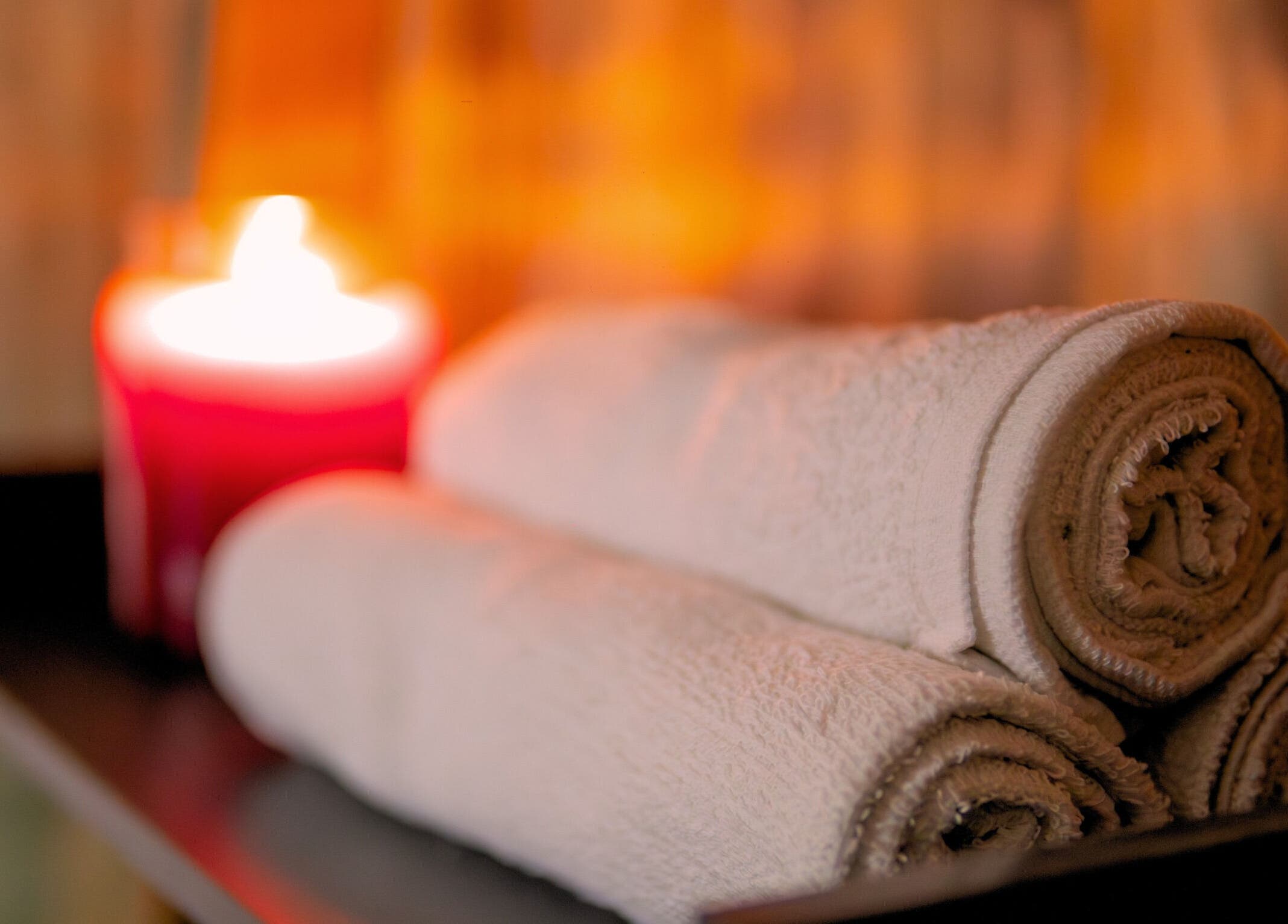 Cozy spa scene with towels and a candle at Absolute Fitness Active Therapy Lounge, Bridgetown, Saint Michael, BB.