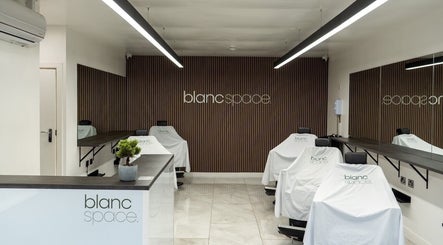 Inside blanc space, Manchester, England, GB. Minimalist salon interior with sleek design and covered chairs.