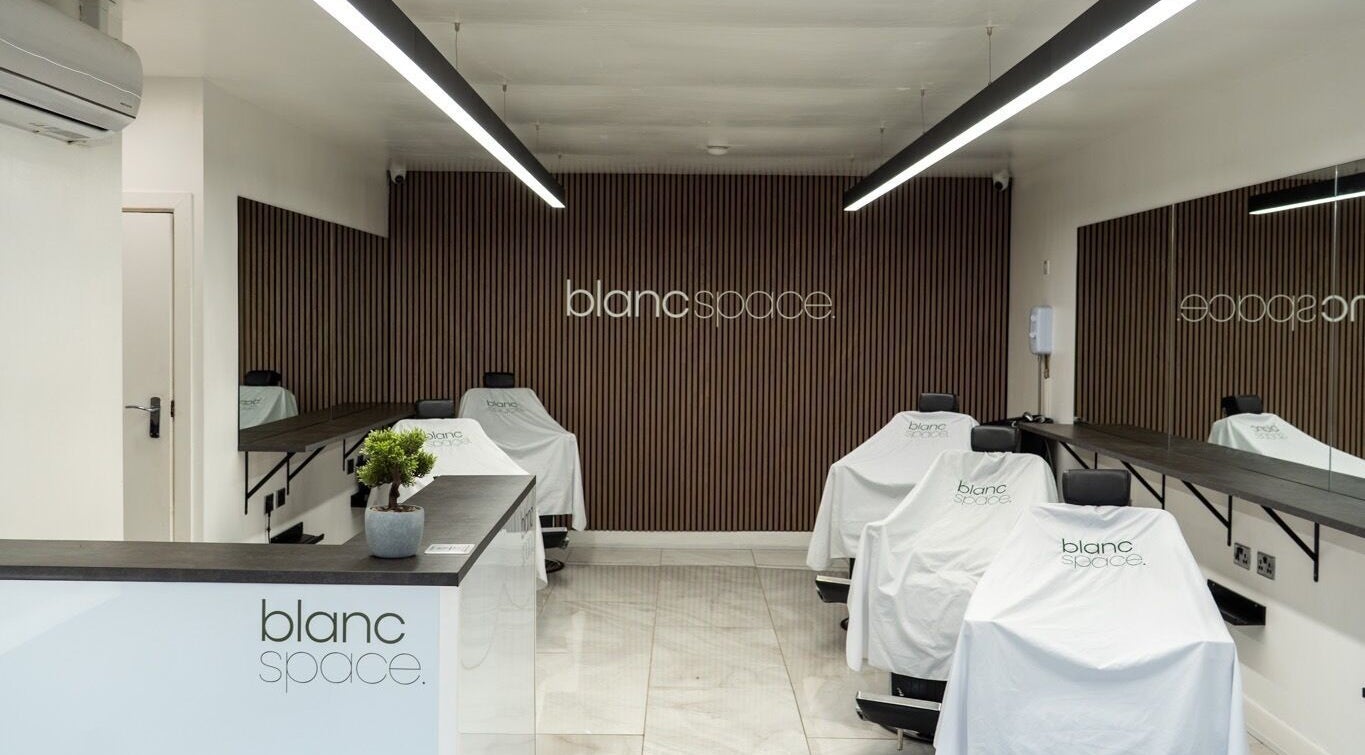 Inside blanc space, Manchester, England, GB. Minimalist salon interior with sleek design and covered chairs.