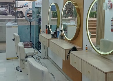Interior moderno de Sin Límites en Miraflores, Provincia De Lima, PE con espejos dorados y sillas blancas.