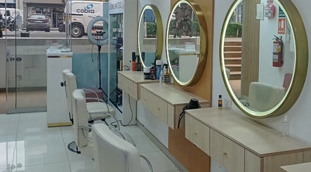 Interior moderno de Sin Límites en Miraflores, Provincia De Lima, PE con espejos dorados y sillas blancas.