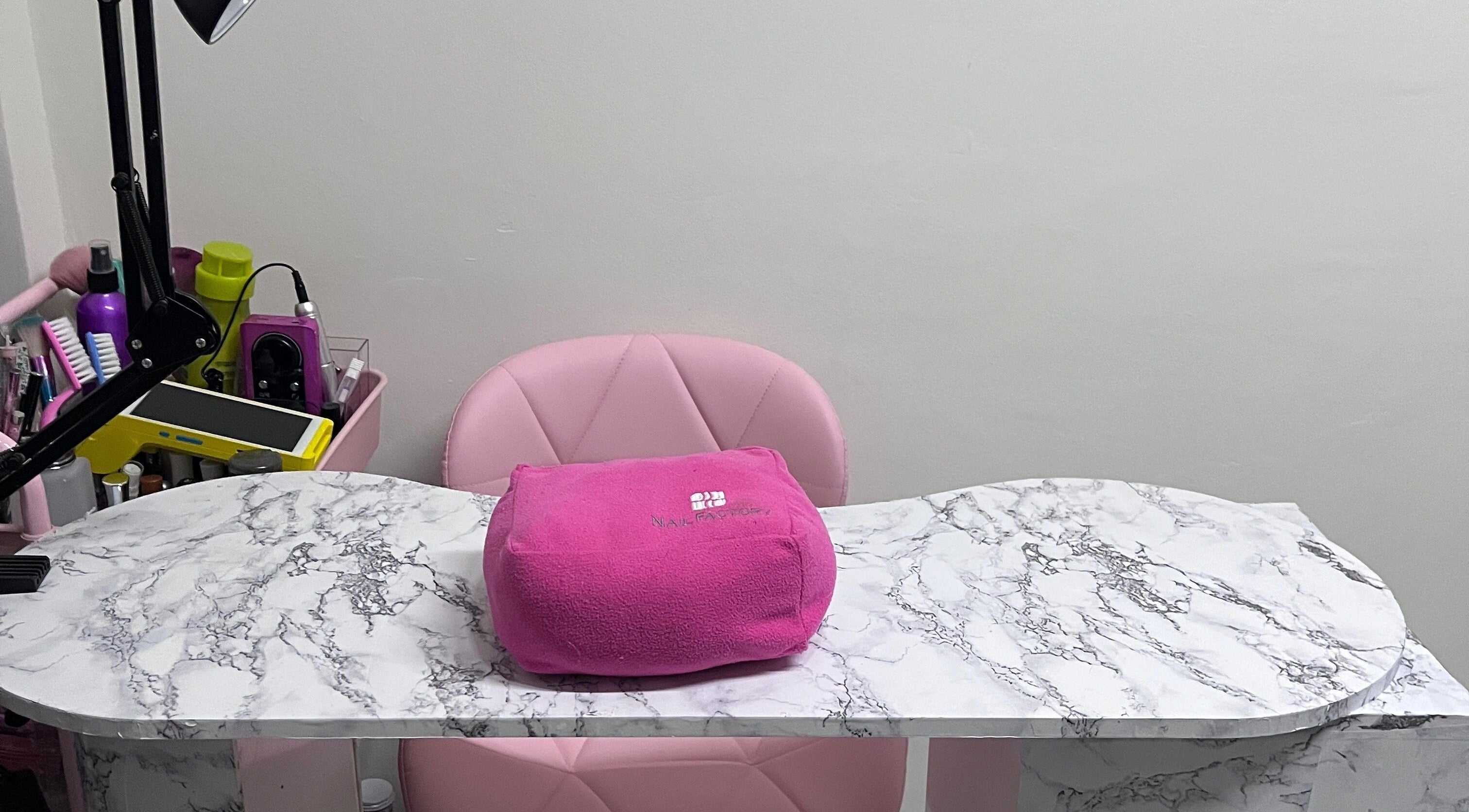 Mesa de manicura elegante en Beauty Nails Dru, Ciudad De México, MX, con silla rosa y lámpara moderna.