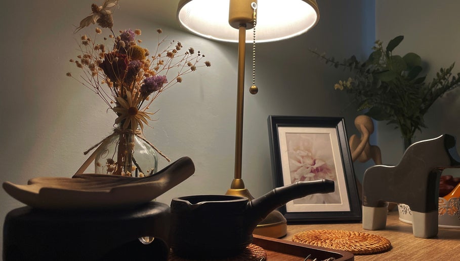 A serene decor setup at Pearl BodyCare, Bunbury, Western Australia, AU, featuring a lamp, dried flowers, and art.