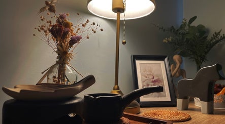 A serene decor setup at Pearl BodyCare, Bunbury, Western Australia, AU, featuring a lamp, dried flowers, and art.
