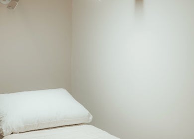 Cozy treatment room at Rejuve Aesthetica, Sydney, New South Wales, AU showcasing a crisp white bed.