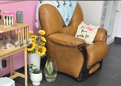 Canto acolhedor em Sony Nail's, Santa Maria Da Feira, Aveiro, PT, com poltrona marrom e flores vibrantes.