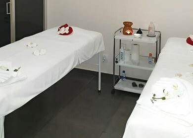 Sala de massagem dupla no Amor de Pele em Amadora, Lisboa, PT, com mesas brancas e decoração relaxante.