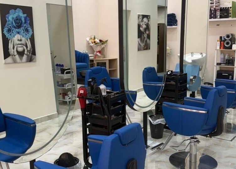 Elegant interior of Queens Salon in Ajman, AE, featuring blue chairs and artistic decor.