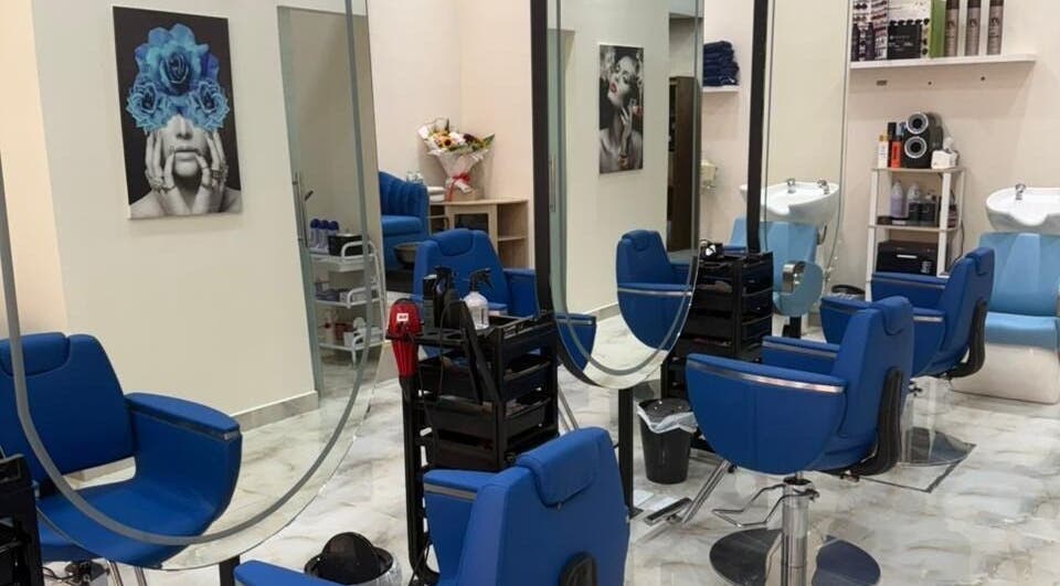 Elegant interior of Queens Salon in Ajman, AE, featuring blue chairs and artistic decor.