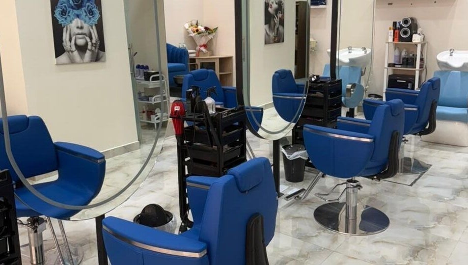 Stylish salon interior at Queens Salon, Ajman, AE with blue chairs, mirrors, and modern decor.