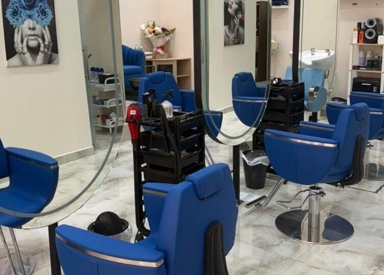 Stylish salon interior at Queens Salon, Ajman, AE with blue chairs, mirrors, and modern decor.