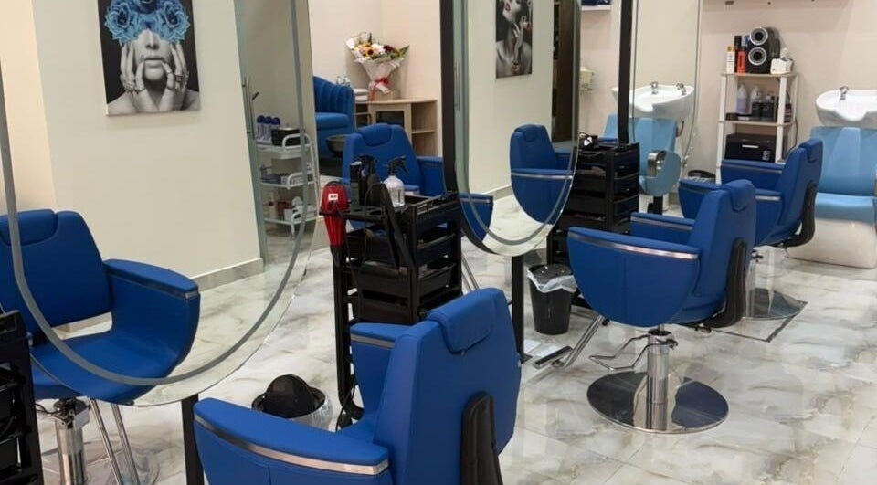 Stylish salon interior at Queens Salon, Ajman, AE with blue chairs, mirrors, and modern decor.
