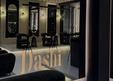 Modern interior of DASHI Beauty in Seeb, Muscat Governorate, OM with chic black chairs and illuminated mirrors.