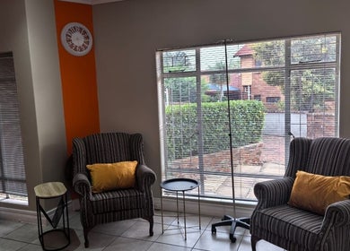 Relaxation area at NASIMISA: Health & Wellness Hub, Pretoria, Gauteng, ZA with striped chairs and orange pillows.